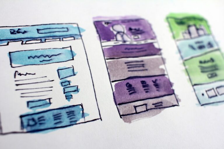 Three hand-drawn and watercolor-painted website wireframes are shown side by side, each with distinct color schemes and content block layouts.